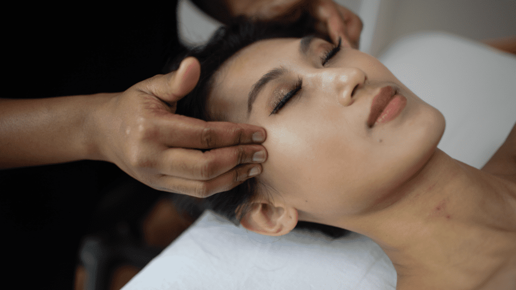 woman lying down with a medical aesthetician's hands on her temples